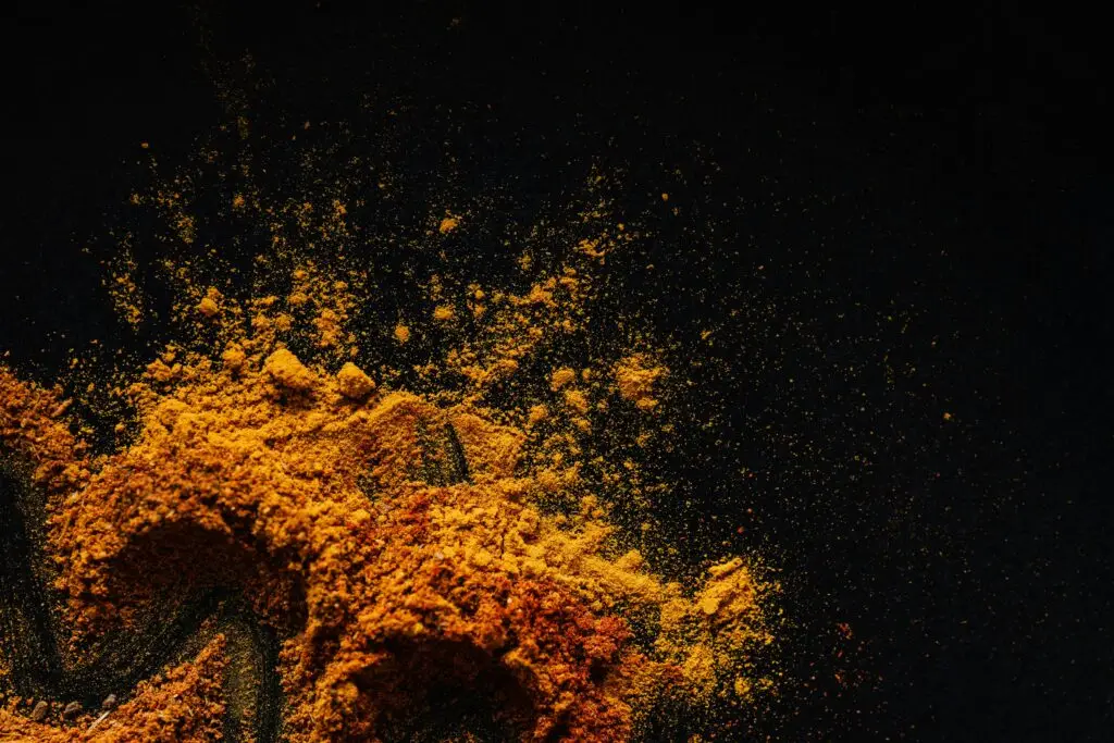 Colorful and aromatic spices spilled on a dark surface, showcasing culinary diversity.